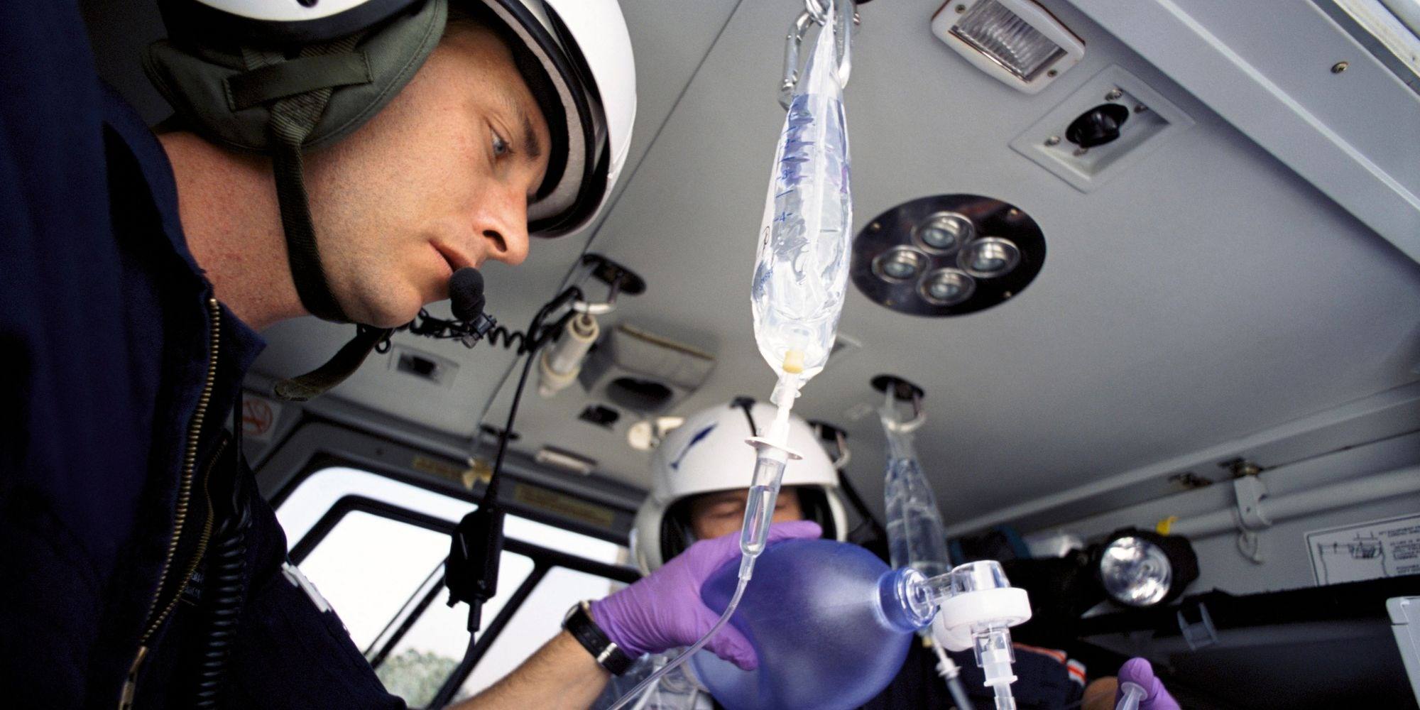 Two paramedics in a helicopter tending to a patient with an IV bag