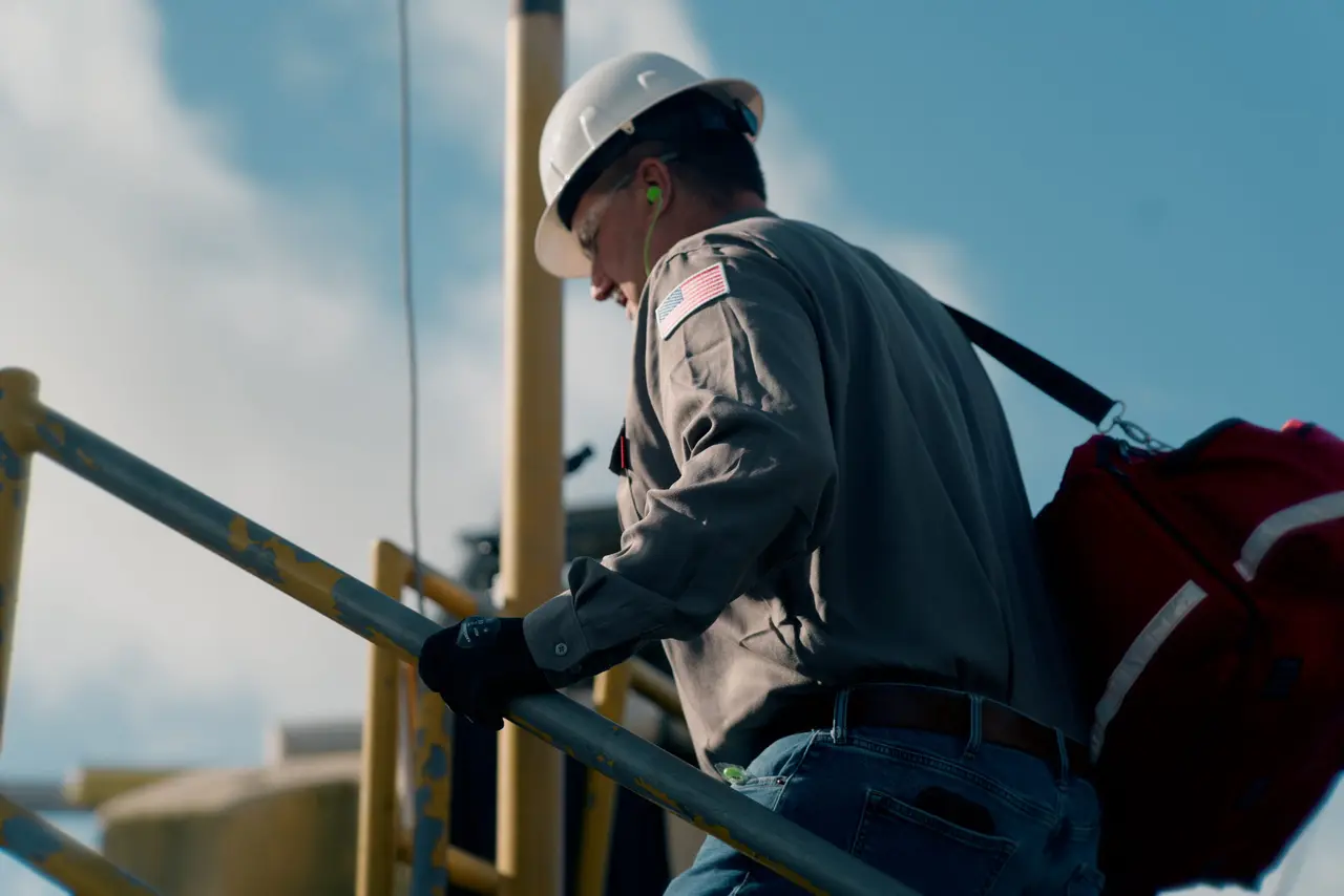 An On Site medic carrying a response bag up rig stairs toward an incident