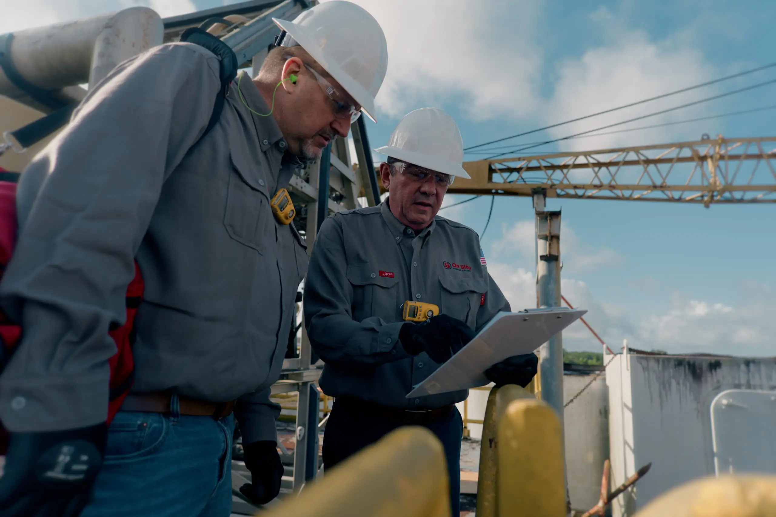 Two On Site safety leads conducting a site walk with a gas detector and audit clipboard