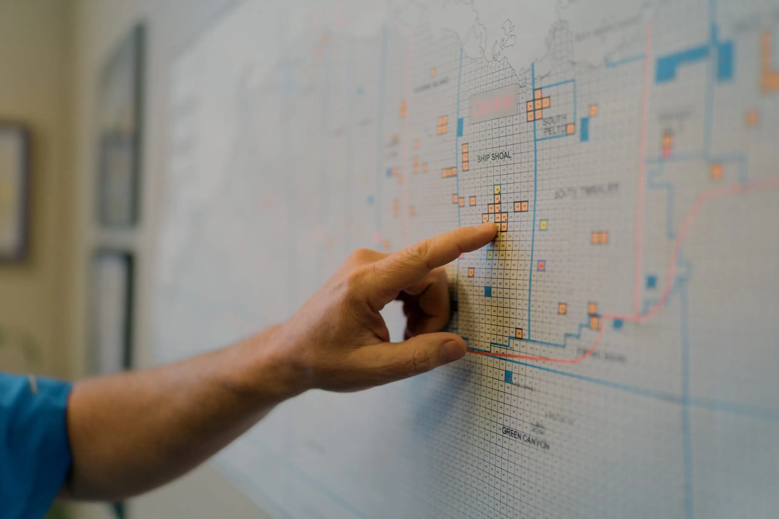 An On Site coordinator pointing at offshore lease blocks on a Gulf of Mexico operations map